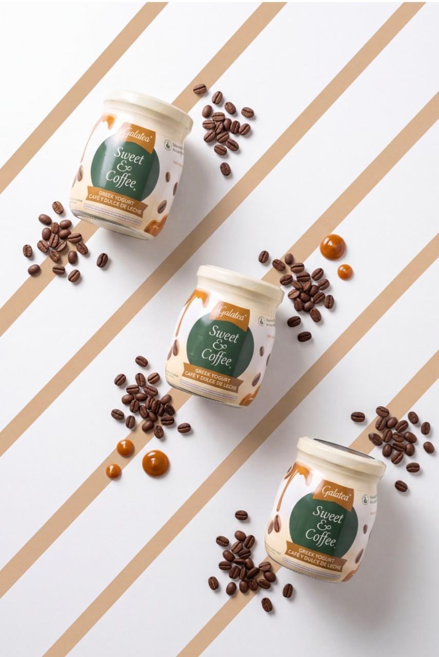 Tres envases de yogurt colocados en diagonal junto a pequeños frutos sobre un fondo claro.